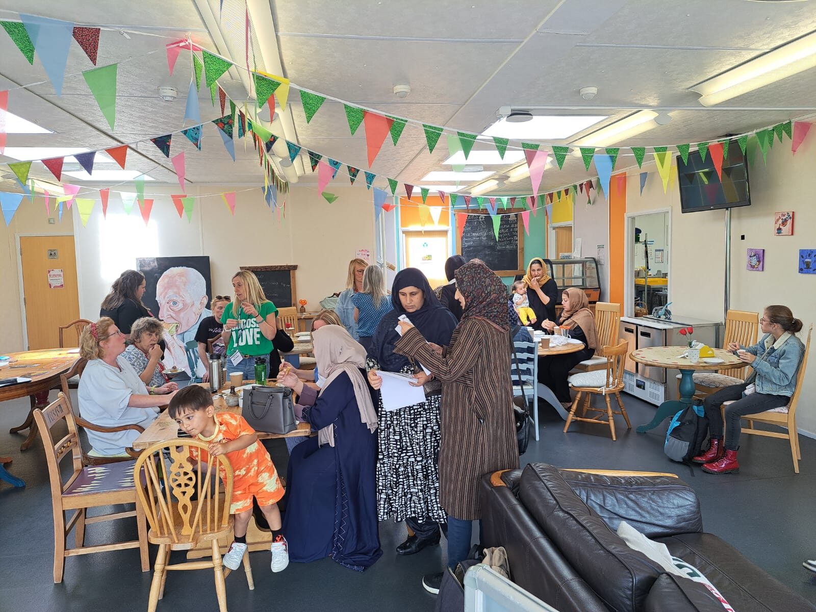 A busy community hub with people meeting around tables